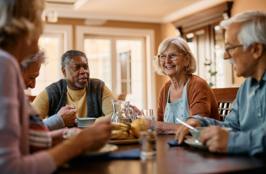 A group of senior adults sitting around a table, eating and enjoying breakfast while smiling and chatting with each other